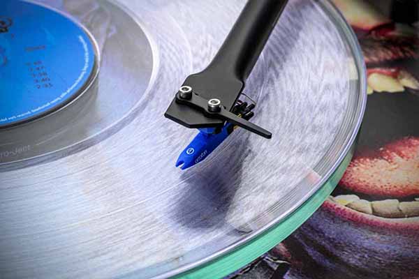 Gros plan sur la cellule et le diamant bleu de la platine Pro-Ject Scorpions édition limitée lisant un vinyle transparent
